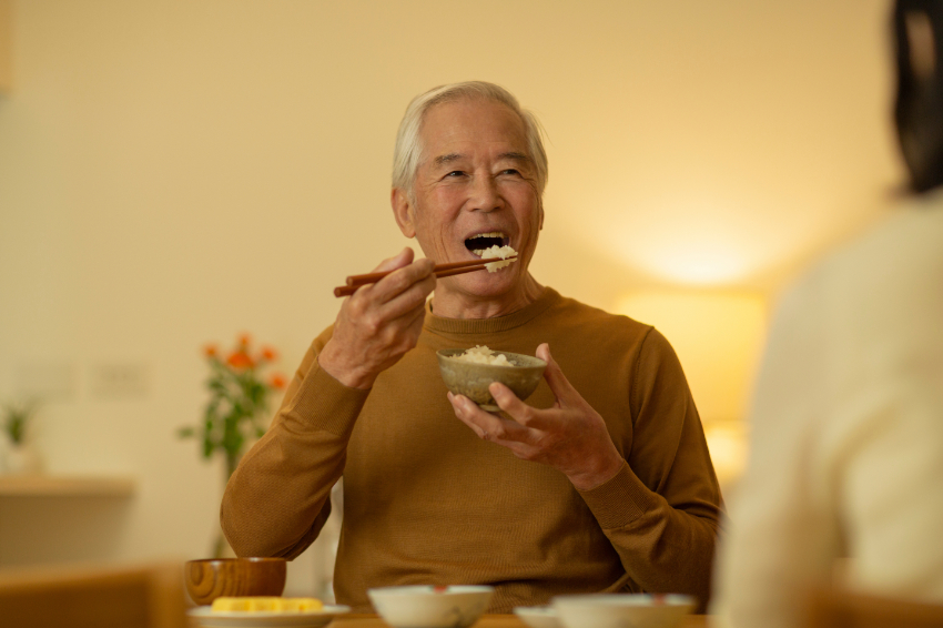 自費の入れ歯治療をして食事を楽しんでいる男性